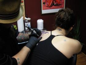 Dreamland Tonight audience member Keelan gets a tattoo of local performer Patrick Elkins at Liquid Swords. She won the tattoo during a falafel-eating contest at the show Friday night.