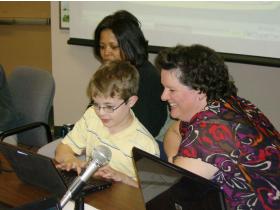 Brick Elementary fourth-grader Patrick Coury, center, shows trustees Yoline Williams, left, and Jennifer La Bombarbe how he has been using Moodle software to practice putting together electrical circuits, during Lincoln's board meeting Monday night.