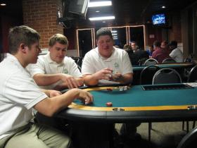 Left to right: Matt Copper, Rob Oas and Garett Cooper sit at a table near a poker game at their new charity poker business, Coop's, in Downtown Ypsilanti.